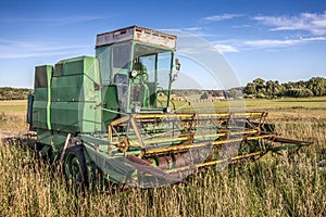 Old green harvester on a field
