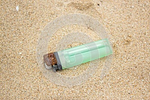 Old green lighter in sand