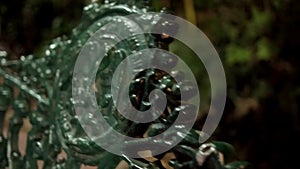 Old green metal bench with Mexican coat of arms and blurry background