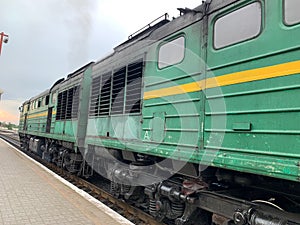 An old green painted locomotive standing at the train station