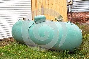 Old green propane tank in backyard of a house