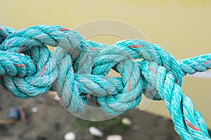 Old green rope knotted on a yellow background. Knot. Insoluble problem concept