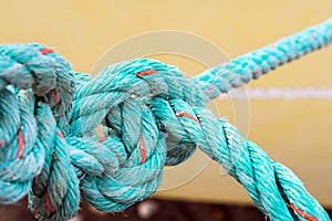 Old green rope knotted on a yellow background. Knot. Insoluble problem concept