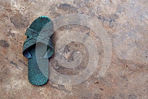 Old green rubber shoes on dirty cement ground for background