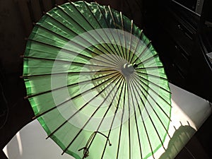 Old green sunshade with wooden ribs and pole