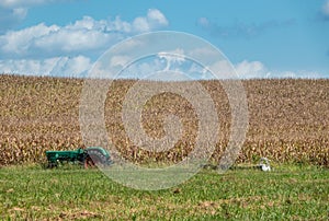 Old green tractor abandoned by the side of corn or wheat field