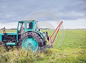 Old green tractor on the background of a rural field, beautiful