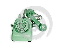 An old green vintage rotary style telephone off the hook