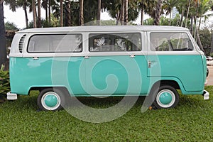 Old green vintage van parked with a large green garden in a beautiful garden