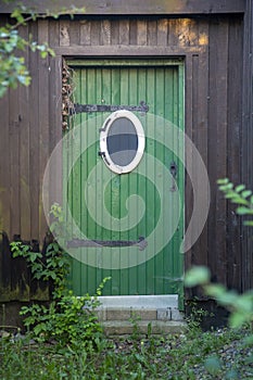 Old green wooden door with a bullseye window