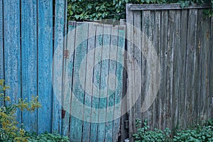 Old green wooden door on a rural blue gray fence