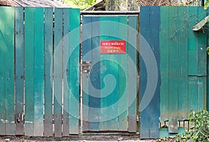 Old green wooden fence and locked door with text `Staff Only` on red label