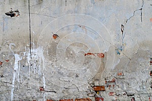 Old grey concrete garage wall with red bricks cracks and spots