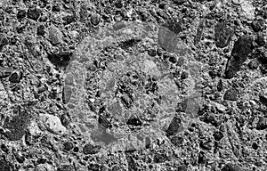 Old grey concrete wall with pieces of stones and cobbles background texture, gray weathered cement wall with pebble texture,