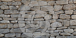 Old Grey stone wall made of large gray small rectangular hewn natural stones