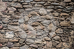 Old grunge dark stone wall built of different stones, texture, pattern irregular background