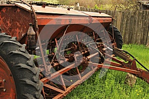 Old grunge Seeding machines Standing on the grass After the end of sowing. Old equipment. Decline in agriculture