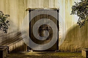 The old grunge wood door with the shade and shadow of the tree on the grunge wall at the night time