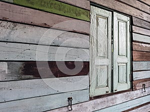 Old grunged wooden window frame painted white vintage with old colourful plywood wall. Antique window frame and old panes. Old