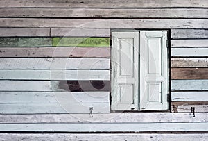 Old grunged wooden window frame painted white vintage with old colourful plywood wall. Antique window frame and old panes. Old