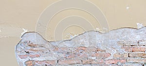 Old grungy red brick wall with peeled beige stucco background. Vintage retro plaster wall with dirty cracked scratched
