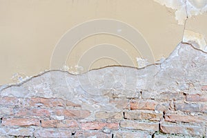 Old grungy red brick wall with peeled beige stucco background. Vintage retro plaster wall with dirty cracked scratched