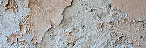 Old grungy weathered wall background texture. Beige dirty peeled plaster wall with falling off flakes of paint