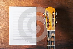 Old guitar on a wooden table. white sheet of musical notes for recording. inspiration concept