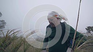 Old guy on a foggy mountain observing the view and talking on the camera.