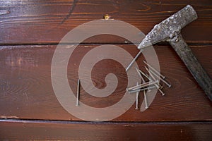 Old hammer and nails on wooden background.