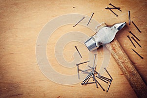 Old hammer and nails on wooden rustic background, working tools from above