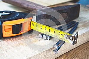 Old hammer with nails and a yellow ruler of roulette on a blackboard background. Tools for construction work