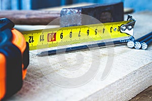 Old hammer with nails and a yellow ruler of roulette on a blackboard background. Tools for construction work