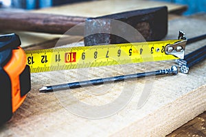 Old hammer with nails and a yellow ruler of roulette on a blackboard background. Tools for construction work