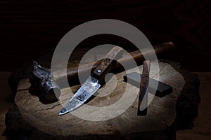 Old hammer and old knife. Vintage tools. Still life of tools. Knife and whetstones. Beam of light in the center.