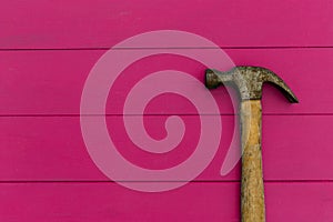 Old hammer on pink wood texture background