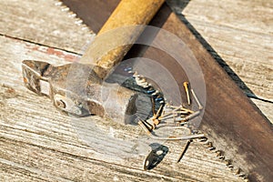 Old hammer and and saw on wooden table