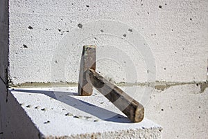 An old hammer on a white foam concrete block from which to build a house from which the shadow falls