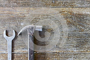 Old hammer and wrench on old wood background