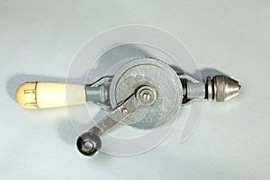 Old hand drill with yellow handle on a gray