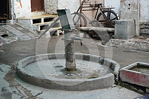 Old hand operated water pump and water containers in rural India. Hand water pump in old city. Very Old Vintage Hand Manual Pump