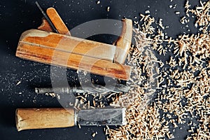 Old hand plane, drill and chisel with wooden shavings on black background. Old woodworking hand tool. Copy, empty space for text