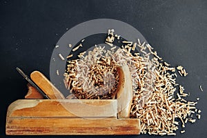 Old hand plane and wood shavings on black background. Old woodworking hand too on a black background. Copy, empty space for text