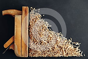 Old hand plane and wood shavings on black background. Old woodworking hand too on a black background. Copy, empty space for text