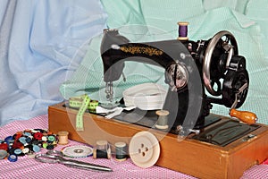 An old, hand sewing machine with a needle, retro coils with colored threads, bright buttons and pieces of colored cotton fabric