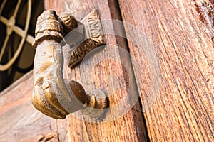 Old hand-shaped knob to knock on an old wooden door