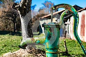 Old hand water pump on a well in the garden, watering and saving water, rural environnement photo