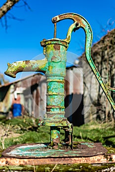 Old hand water pump on a well in the garden, watering and saving water, rural environnement
