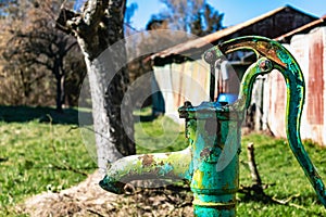 Old hand water pump on a well in the garden, watering and saving water, rural environnement