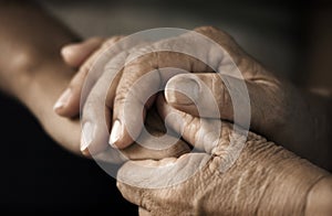 Le mani di una donna anziana che tiene la mano di una giovane donna.